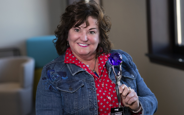 Joanie McMahon holding go beyond award